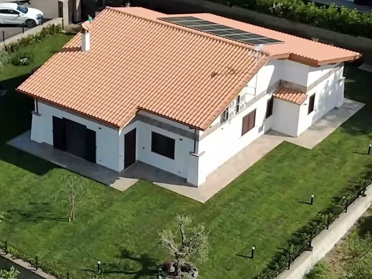 Lo stesso giardino finito: prato attecchito su tutto il perimetro della casa, camminamenti e faretti lungo il bordo